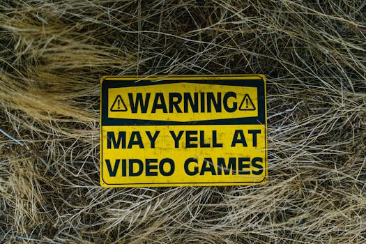 A funny yellow warning sign on grass reading 'Warning May Yell at Video Games'.