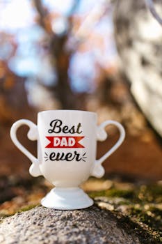 Decorative trophy-shaped mug with 'Best Dad Ever' message on rocky background, perfect for Father's Day gift.