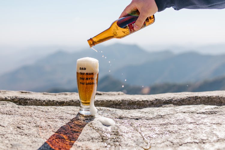 A Person Pouring Beer On Drinking Glass