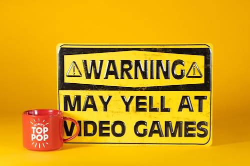 Yellow and Black Warning Sign Beside a Red Mug