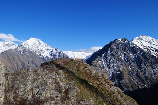 Stunning view of snow-capped mountains with clear blue sky and rocky foreground.