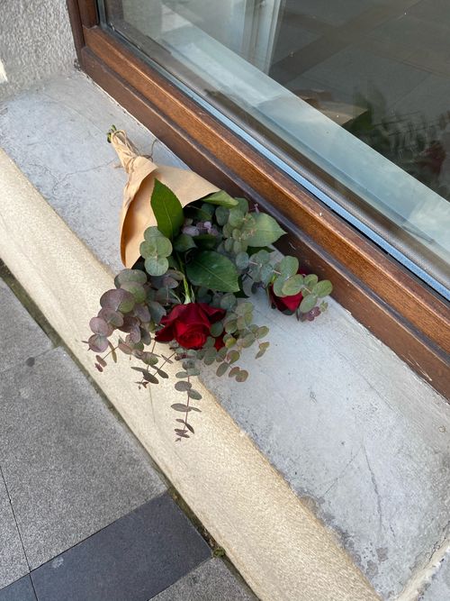 Free A bouquet of red roses with eucalyptus leaves on a concrete windowsill in Beşiktaş, Istanbul. Stock Photo
