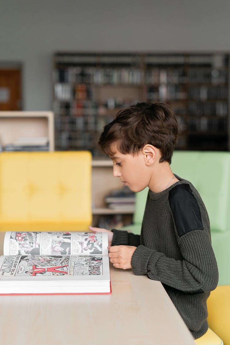 A Side View Of A Young Boy Reading Book