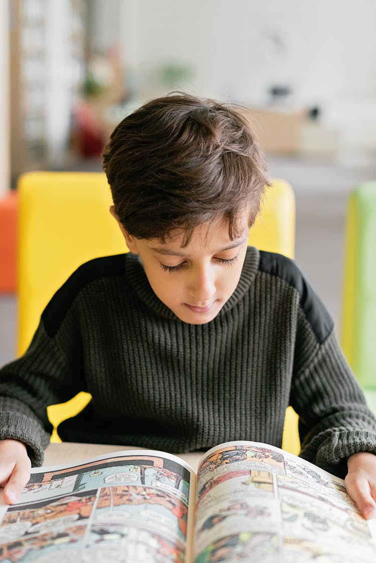 Boy In Black Sweatshirt Sitting And Reading A Comics 