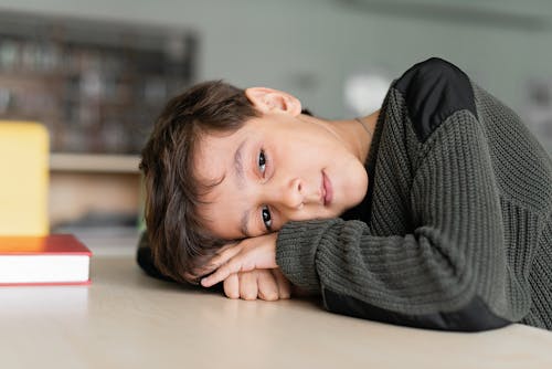 Free Boy in Black Sweater Head Down on the Table  Stock Photo