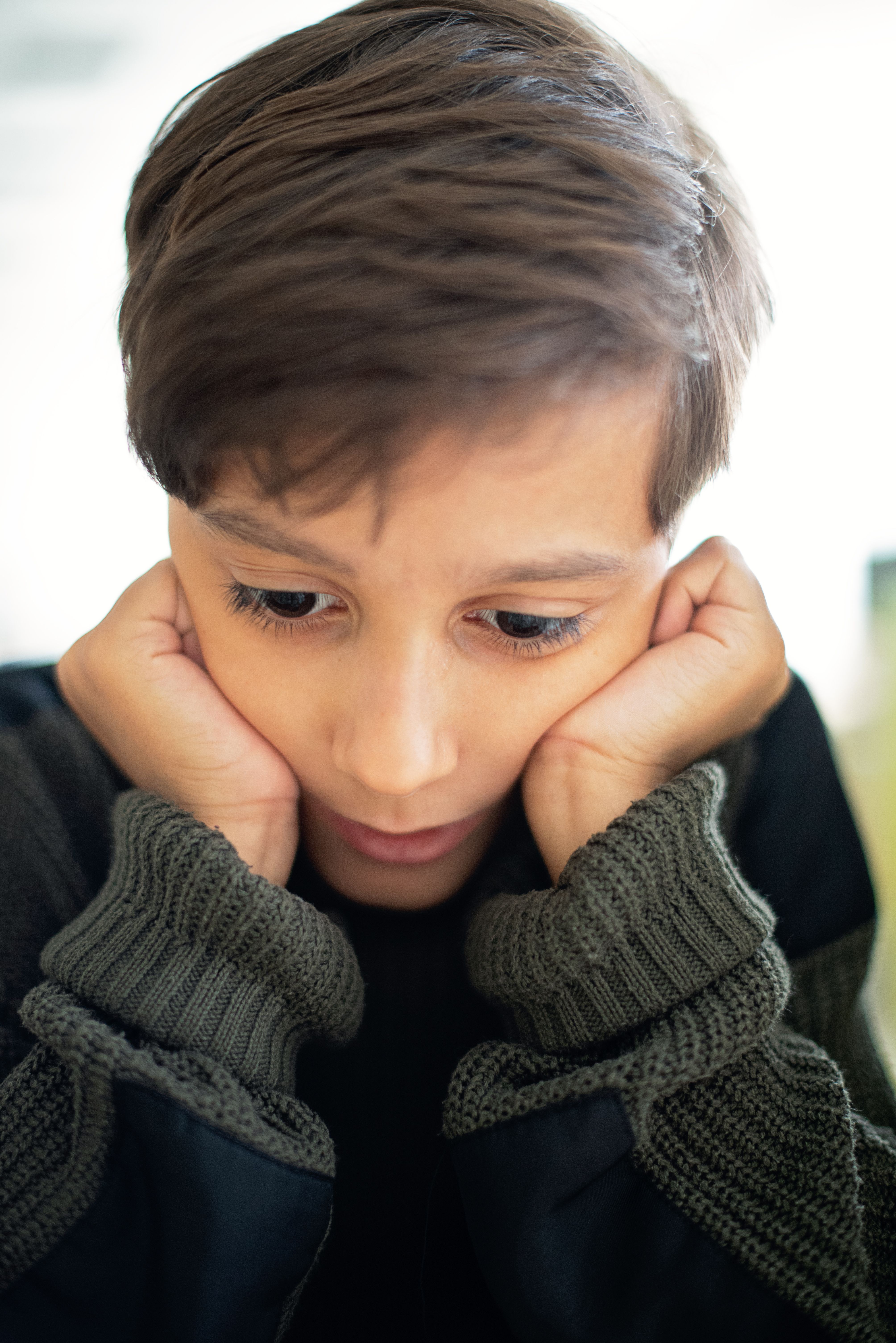 Child leaning head on arms, pensive