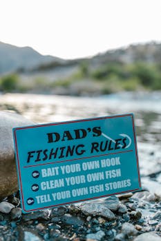 Humorous fishing sign with rules at a scenic river location.