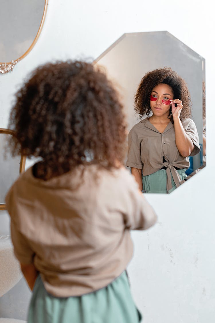 A Woman With Red Sunglasses Looking At The Mirror