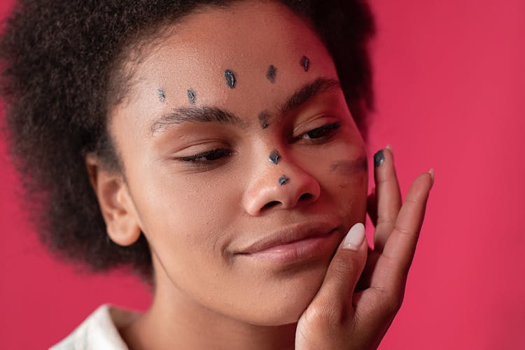 Woman Applying Cream On Her Face