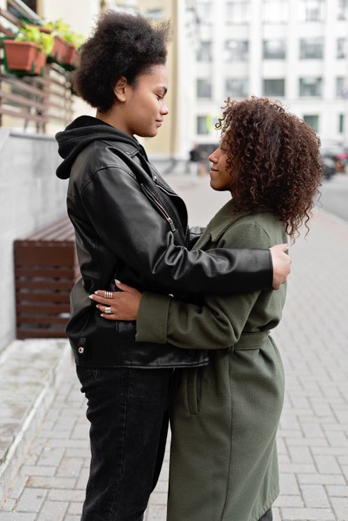 Free Couple standing face-to-face and embracing on a city sidewalk. Stock Photo