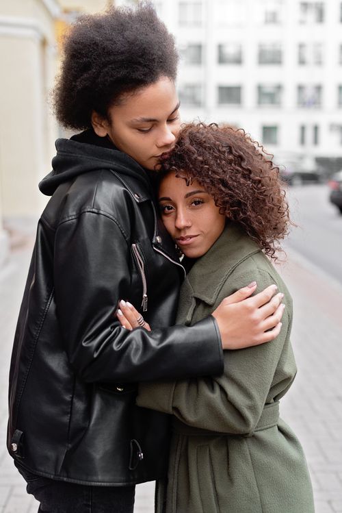 Free Romantic same-sex couple embracing affectionately on a city street. Stock Photo