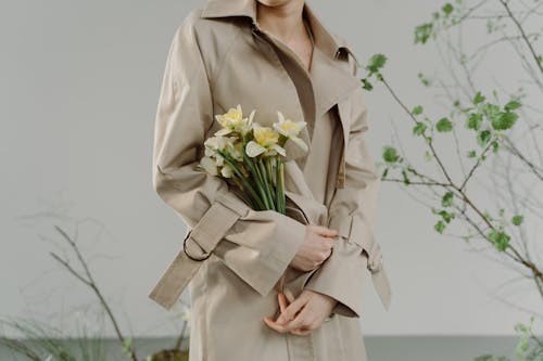 Woman in Brown Trench Coat Holding White Daffodils