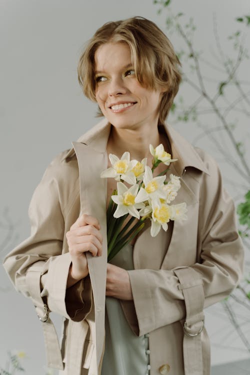 Woman in Brown Coat Holding Daffodil Flowers