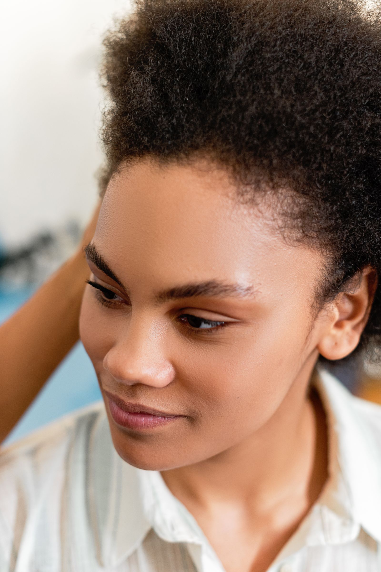 A close portrait of a Black woman with natural hair and a visible hairline. Central centrifugal cicatricial alopecia starts at the crown and is treatable when caught early.