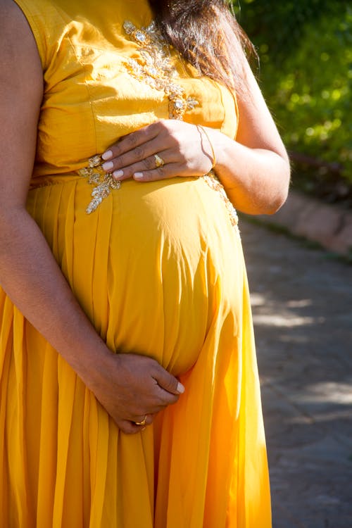 Free Woman in Yellow Dress Holding Her Stomach Stock Photo