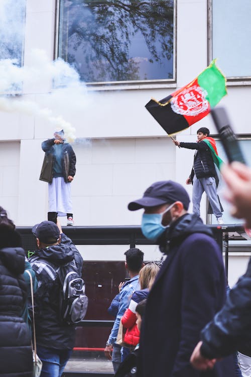 Free Two Men Standing on a Ledge Doing a Protest with Smoke Bomb and Flag Stock Photo
