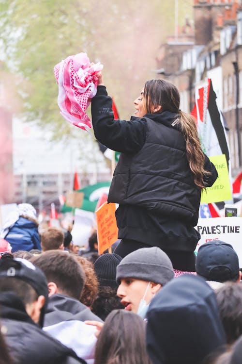 A Woman in Black Jacket Holding a Pink Cloth in a Rally