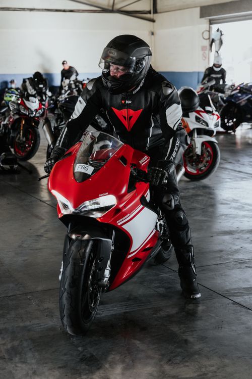 Free Motorcyclist in gear ready to ride a red sport bike in an urban garage setting. Stock Photo