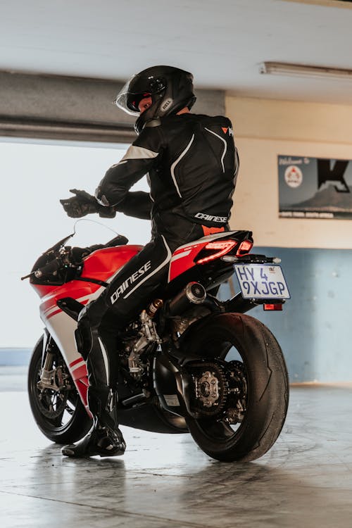 Man in Black and Red Motorcycle Suit Riding Red and Black Sports Bike