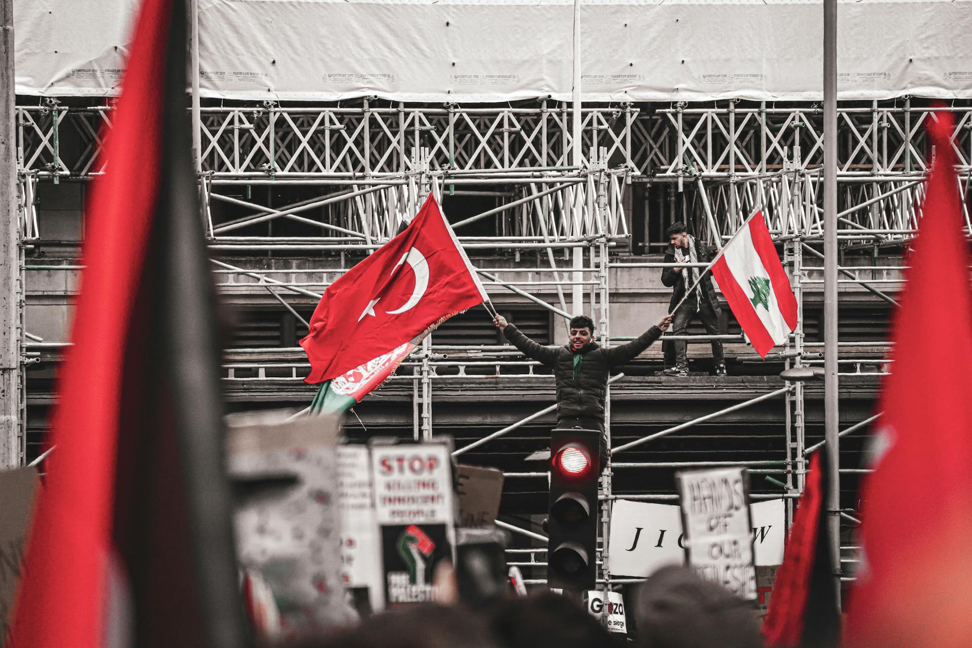 Protester holding Turkish and Lebanese flags during urban demonstration.