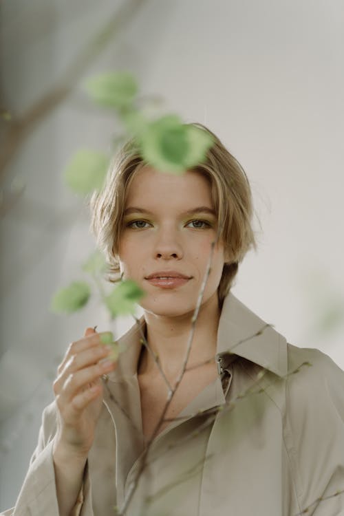 Woman in Brown Coat Holding Green Leaves