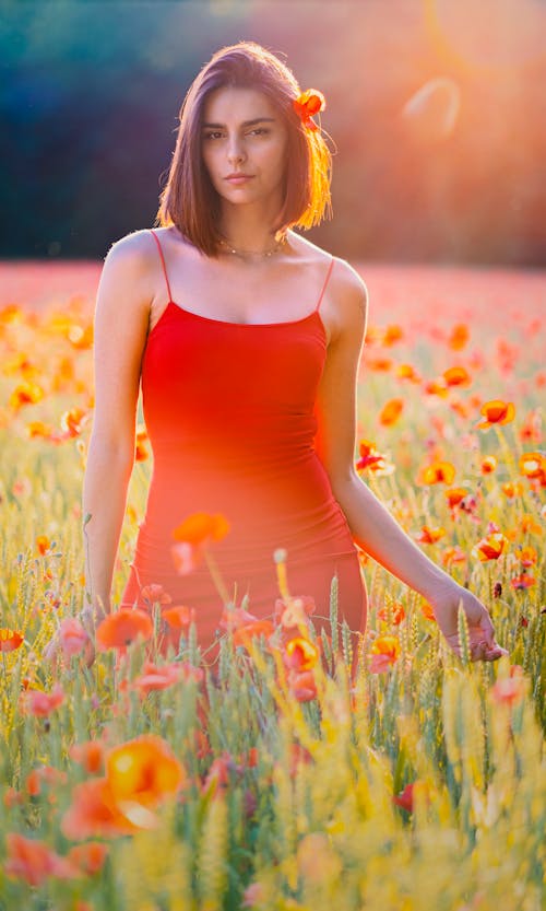 A Woman in Red Dress Standing in the Middle of the Grass Field