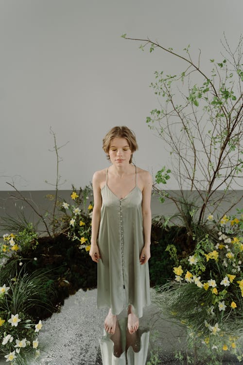 A Woman in Beige Dress Standing beside the Plants