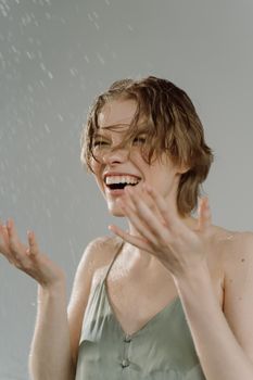 A happy woman with wet hair enjoys a refreshing water splash with laughter.