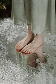 Close-up of bare feet in a puddle, reflecting serenity and tranquility.