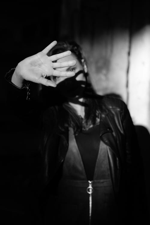 Free Woman in Black Jacket Covering Face with Her Hand Stock Photo