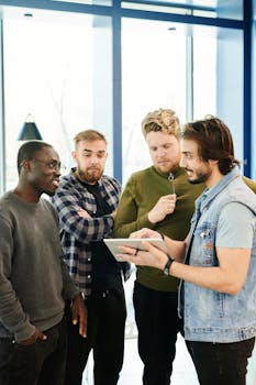 A diverse group of men discussing a digital project using a tablet indoors.
