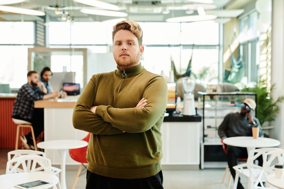Caucasian man posing confidently with arms crossed in a stylish, modern office environment. Caucasian man posing confidently with arms crossed in a stylish, modern office environment.