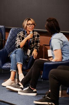 Diverse adults engaging in a casual seminar discussion indoors, featuring denim and plaids.