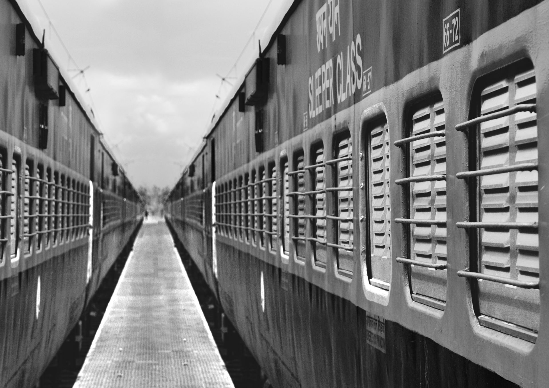 Black and white perspective view of two parallel sleeper class trains, emphasizing symmetry.