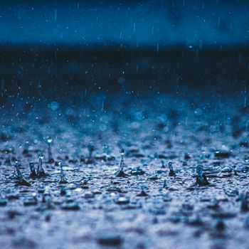 Artistic close-up capturing raindrops splattering on a wet surface, evoking a moody atmosphere.