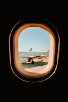 Airplane captured through a window seat during takeoff, showcasing travel vibes and runway.