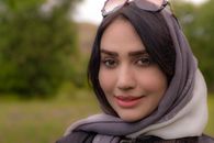 Smiling woman with headscarf outdoors in Iran, vibrant and natural look.