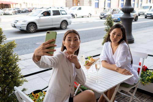 Free Woman in White Long Sleeve Shirt Holding Smartphone Beside Woman in White Long Sleeve Shirt Stock Photo