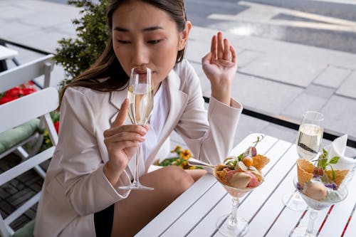 Free Woman in White Blazer Drinking White Wine with Ice Cream on Table Stock Photo