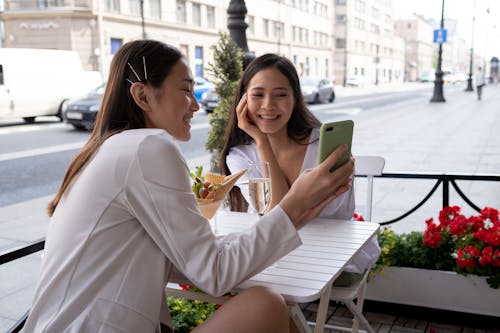 Free A Woman Showing Her Mobile Phone to Her Friend Stock Photo