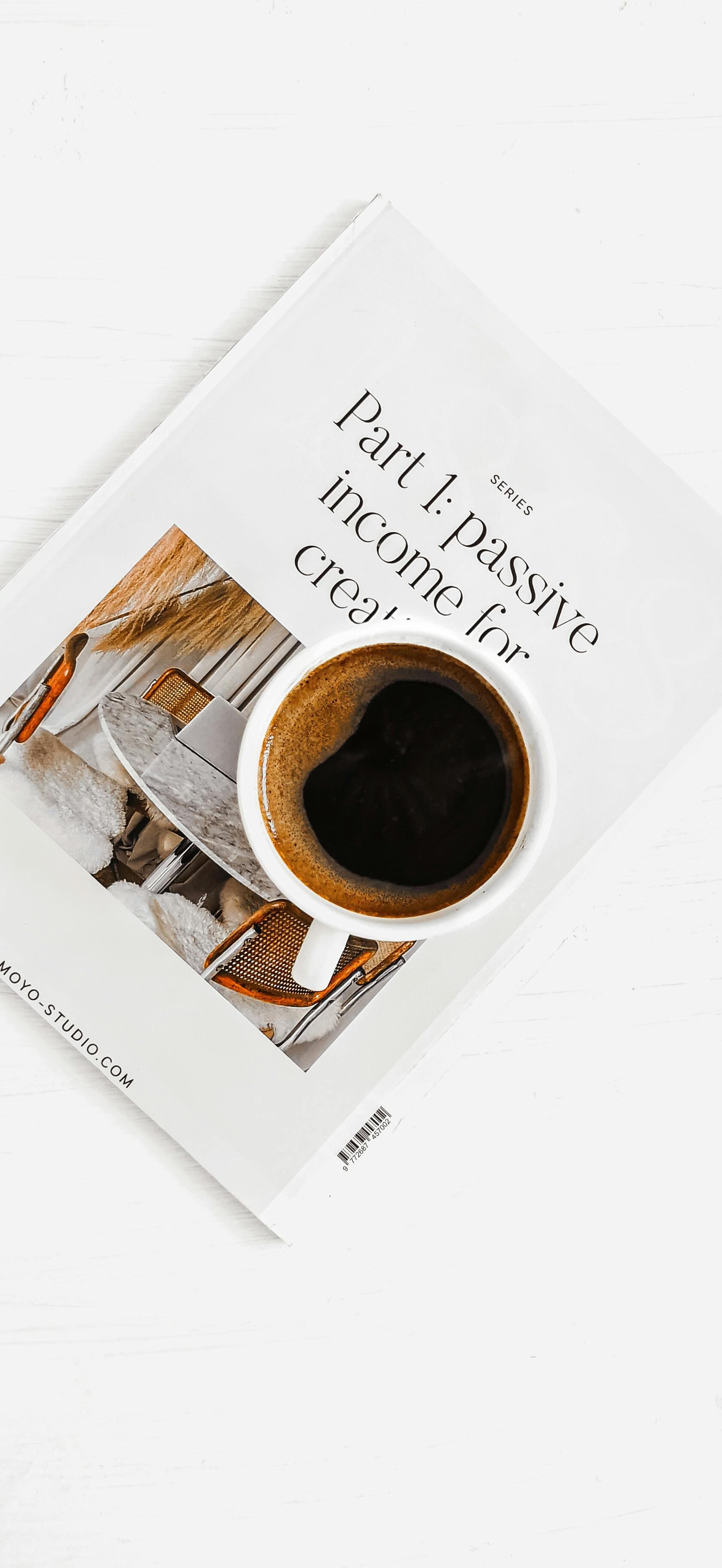Aesthetic flat lay of a coffee cup on a book discussing passive income for creatives.