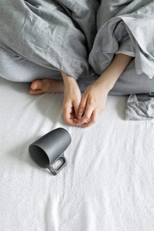Free Cup on the Bed Near the Hands Stock Photo