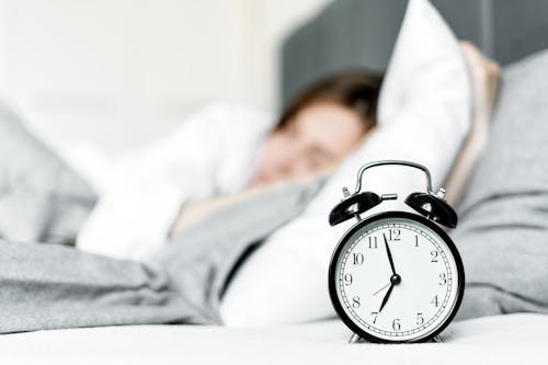 Free An Alarm Clock on Bedside Near a Sleeping Woman Stock Photo