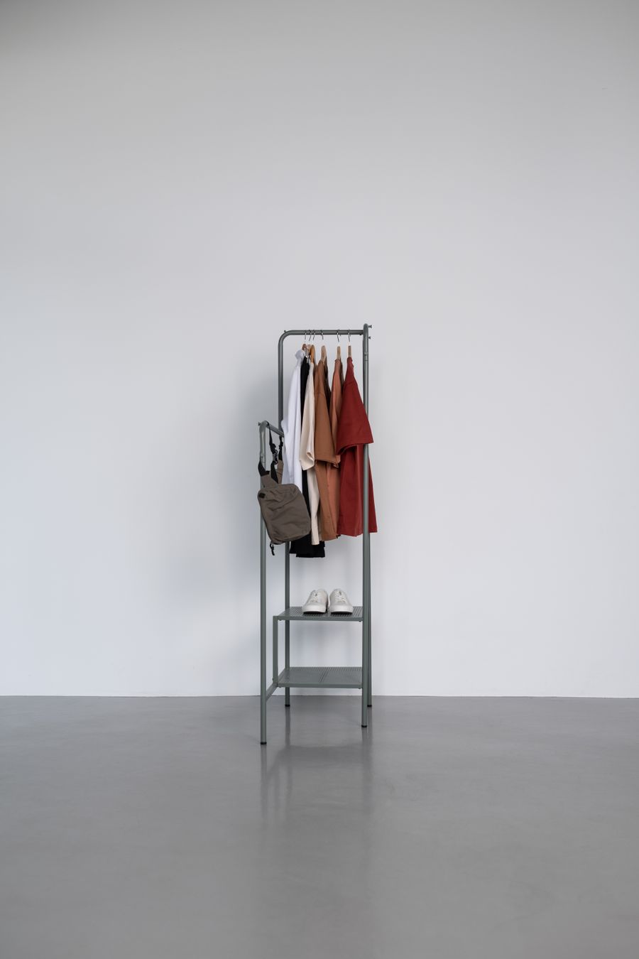 Neutral garments on a slim rail in an empty studio — photo by Ron Lach on Pexels