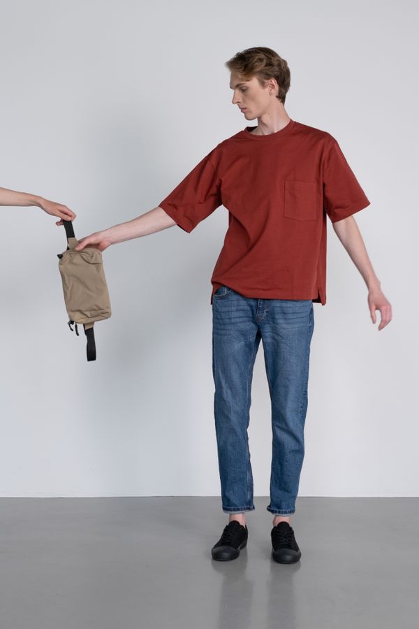 Person holding a compact waist bag against a neutral wall — photo by Ron Lach on Pexels