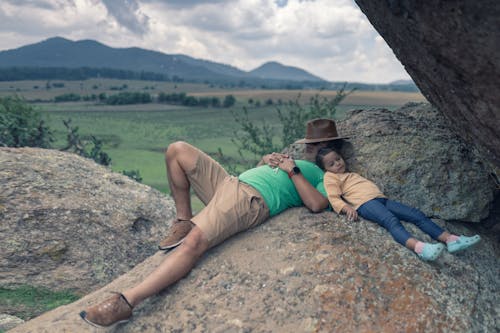 A Father and Daughter Lying on the Rock Formation