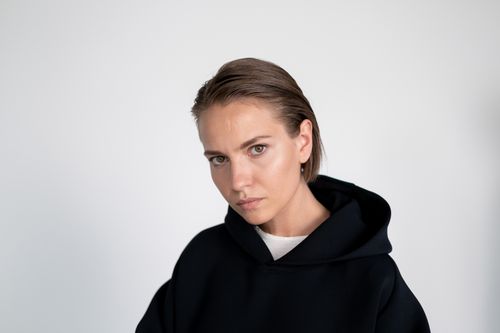 Free Close-up portrait of a woman in a black hoodie against a white background. Perfect for fashion and lifestyle themes. Stock Photo