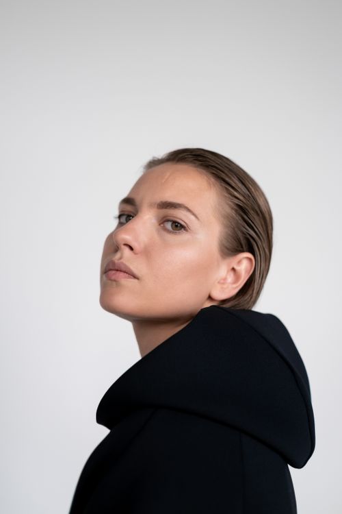 Free Minimalist side view portrait of a woman in a black hoodie with a serene expression. Stock Photo