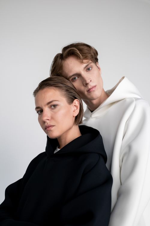 Free Close-up portrait of a stylish young couple in contrasting hoodies against a light background. Stock Photo