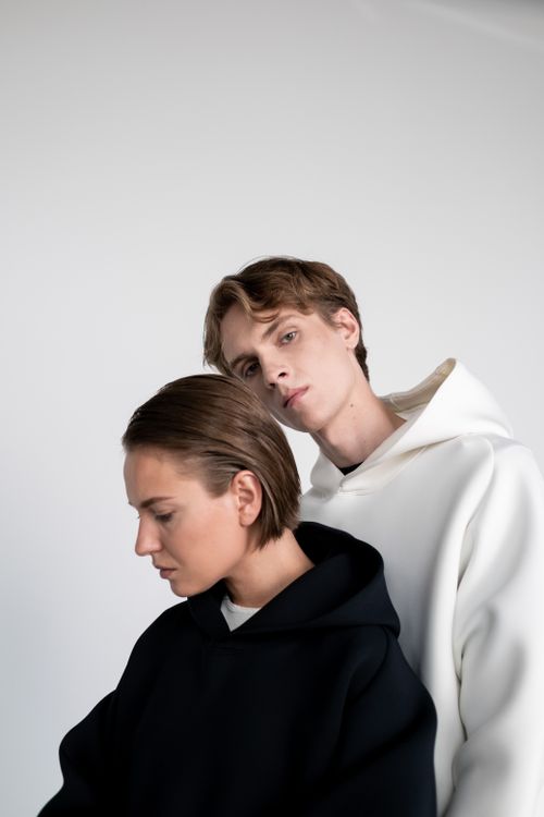 Free Stylish portrait of a couple in modern hoodies against a neutral background. Stock Photo